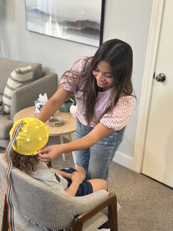 Provider fitting EEG cap on child during neurofeedback brain mapping session